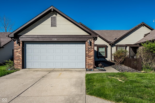 view of front of home featuring brick siding, driveway, a front lawn, and a garage