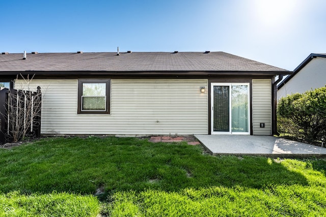 back of house featuring roof with shingles, a patio, and a yard