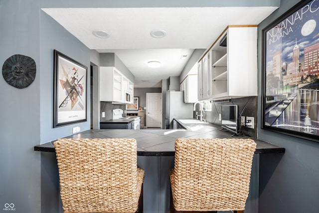 kitchen featuring a sink, open shelves, white cabinetry, and white appliances