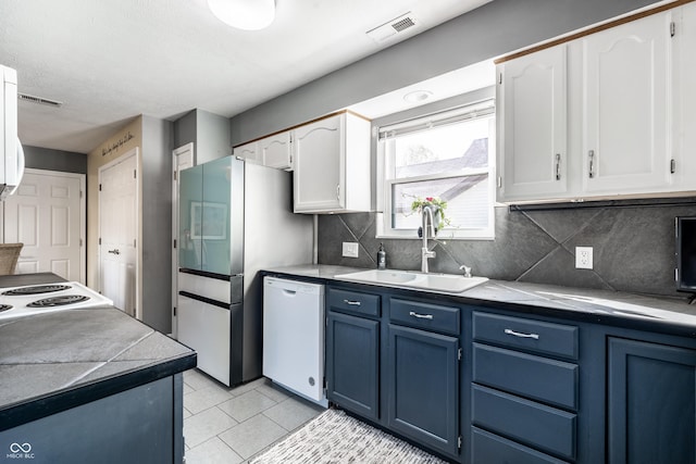 kitchen featuring white cabinets, a sink, dishwasher, visible vents, and blue cabinets