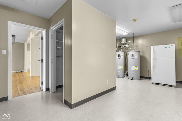 basement featuring freestanding refrigerator, water heater, and baseboards