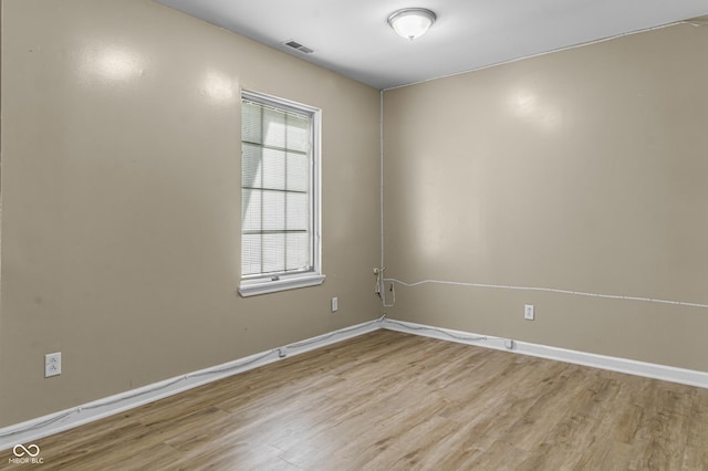 empty room featuring light wood finished floors, visible vents, and baseboards