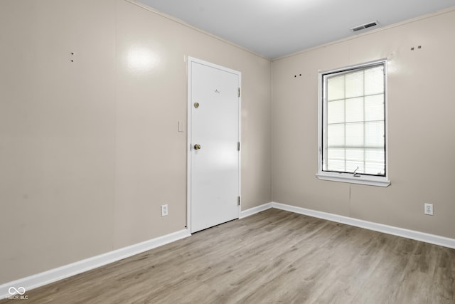 spare room featuring baseboards, visible vents, and wood finished floors