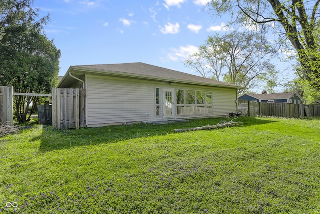 rear view of house featuring a yard and fence