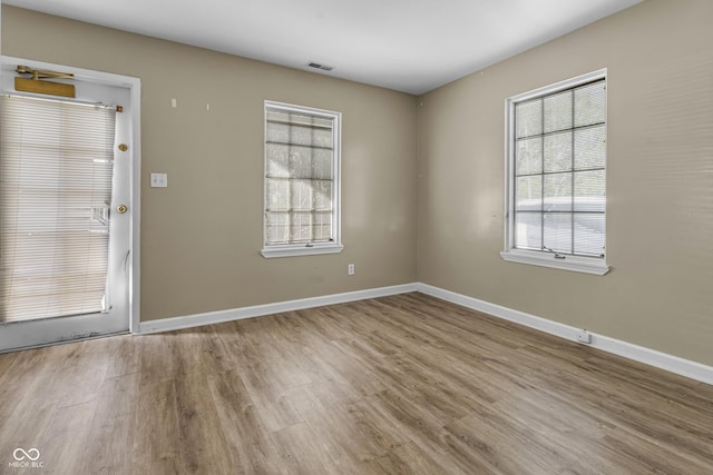 spare room featuring visible vents, wood finished floors, and baseboards