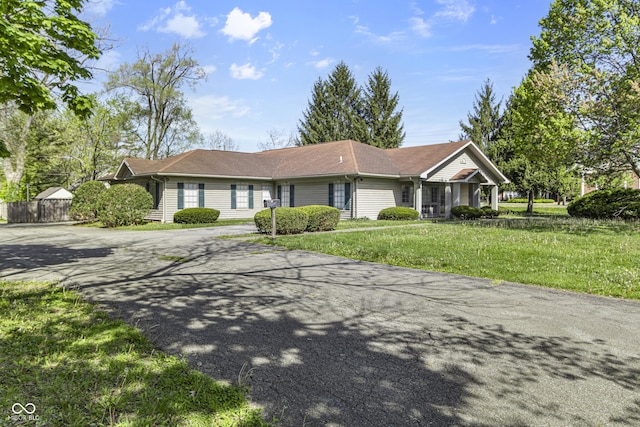 ranch-style house featuring concrete driveway and a front lawn