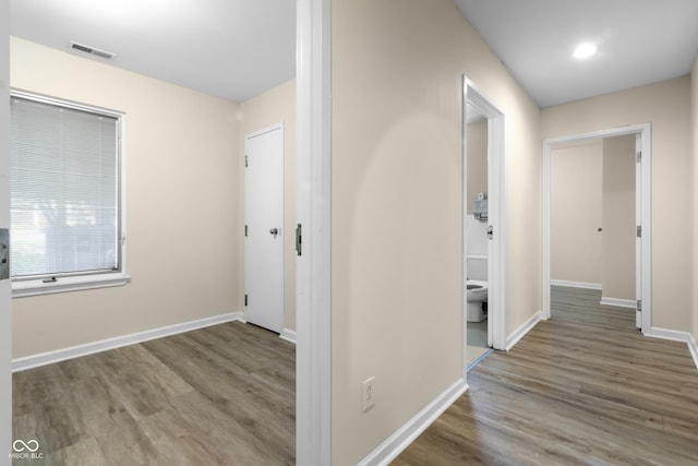 corridor with visible vents, wood finished floors, and baseboards