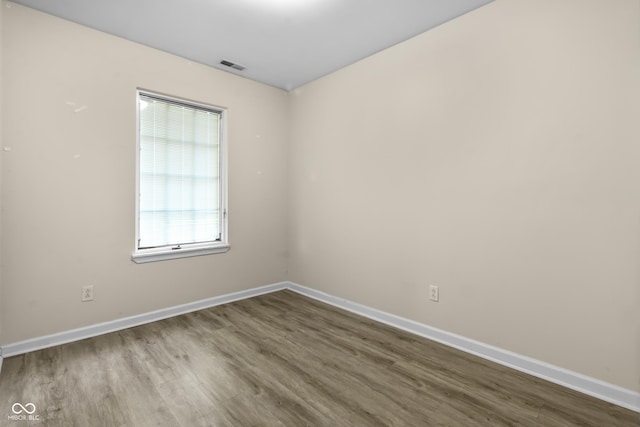 unfurnished room featuring visible vents, wood finished floors, and baseboards