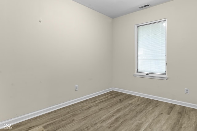 empty room featuring baseboards, visible vents, and wood finished floors