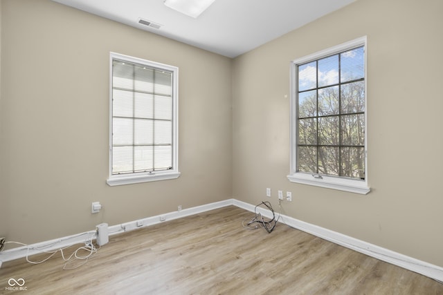 empty room with baseboards, visible vents, and wood finished floors