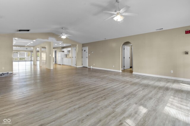 unfurnished living room featuring visible vents, lofted ceiling, ceiling fan, and arched walkways