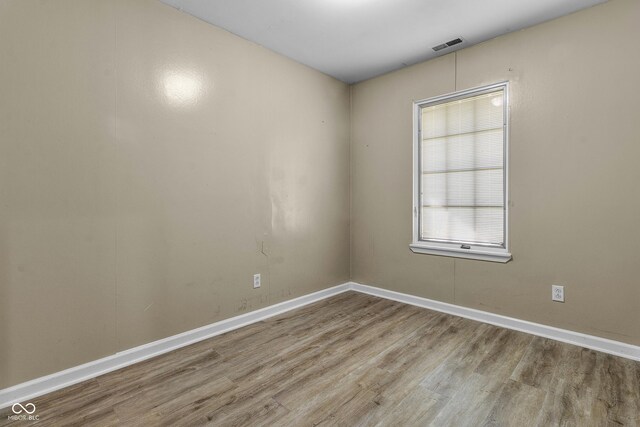 unfurnished room featuring visible vents, wood finished floors, and baseboards
