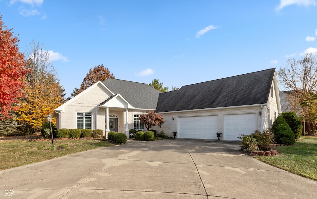 view of front of property featuring concrete driveway, an attached garage, a front yard, brick siding, and a shingled roof