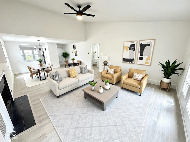 10200 Cheswick Ln, Fishers, IN 46037 - living room featuring light wood-style floors, lofted ceiling, ceiling fan, baseboards, and a fireplace with flush hearth