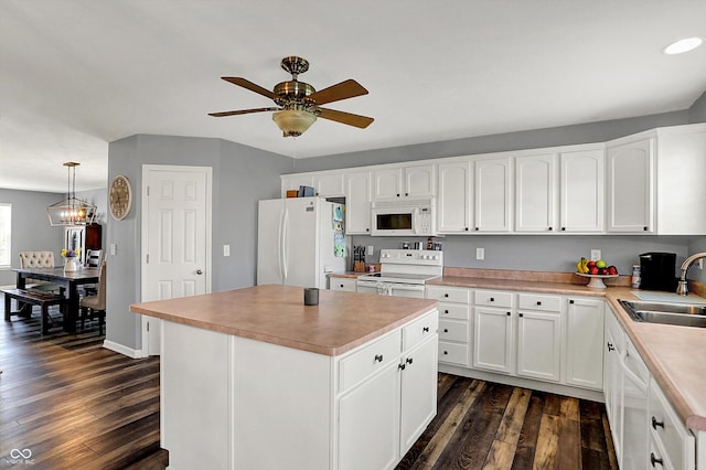 kitchen featuring dark wood finished floors, light countertops, a sink, white appliances, and ceiling fan with notable chandelier