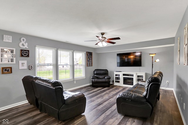 living room with baseboards, ceiling fan, and dark wood-style floors