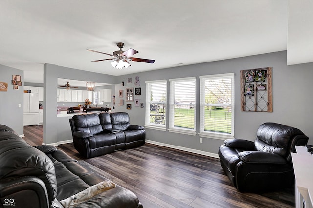 living room with baseboards, ceiling fan, and dark wood-style floors