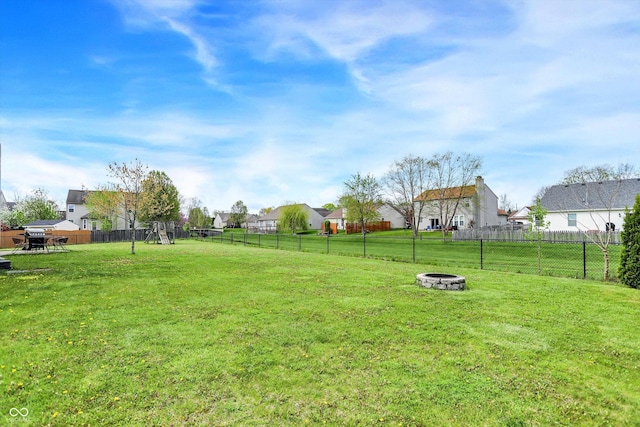 view of yard featuring a fenced backyard, an outdoor fire pit, a residential view, and a playground