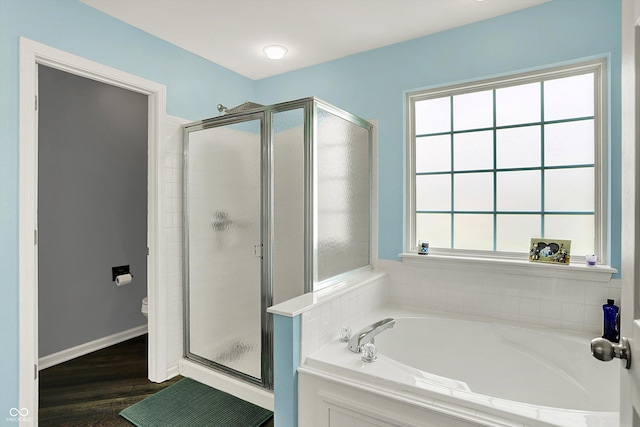 bathroom featuring a bath, wood finished floors, a shower stall, and toilet