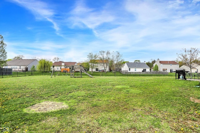 view of yard with fence, a residential view, and a playground