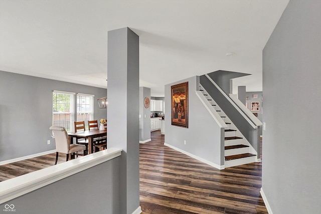 interior space featuring wood finished floors, baseboards, and a notable chandelier
