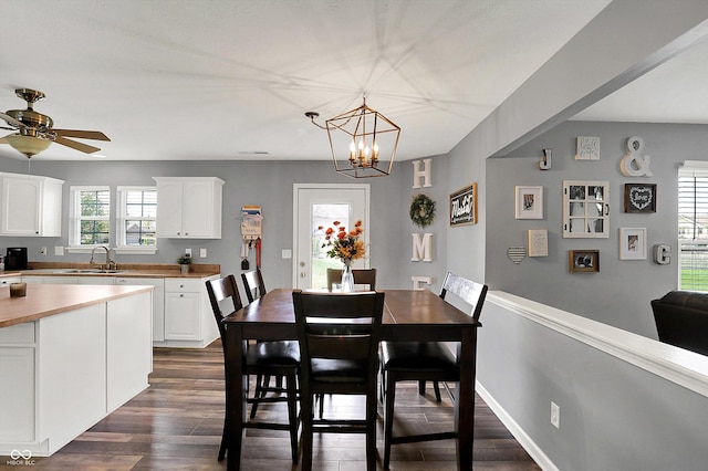 dining area featuring dark wood finished floors and ceiling fan with notable chandelier