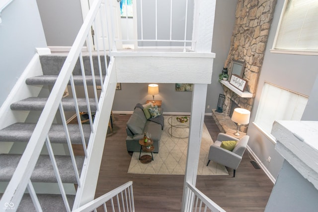 staircase featuring visible vents, baseboards, wood finished floors, and a fireplace