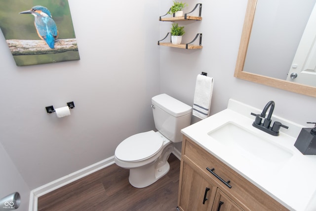 bathroom featuring toilet, baseboards, wood finished floors, and vanity