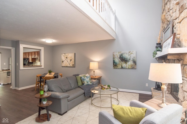 living area featuring baseboards, wood finished floors, and a fireplace