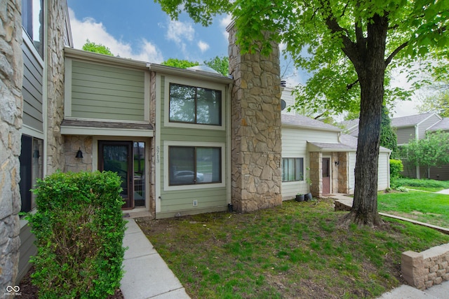 townhome / multi-family property featuring stone siding and a front yard