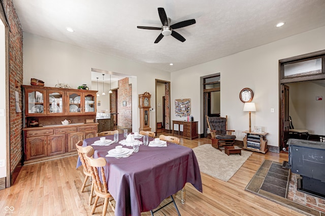 3864 N US Highway 231, Greencastle, IN 46135 - dining area with light wood-style floors, ceiling fan, a wood stove, a textured ceiling, and brick wall
