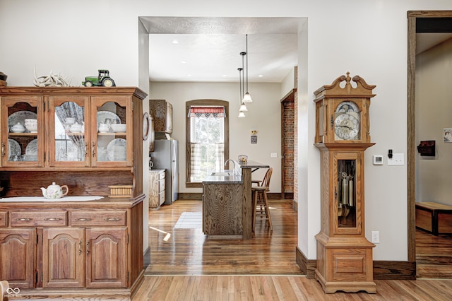 3864 N US Highway 231, Greencastle, IN 46135 - kitchen featuring glass insert cabinets, light wood-style flooring, freestanding refrigerator, and a breakfast bar