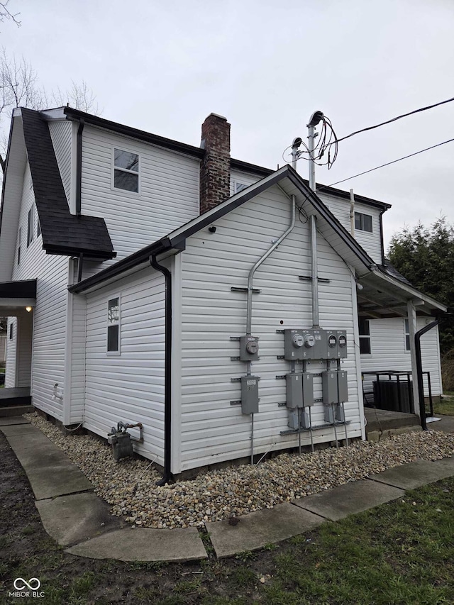 view of home's exterior featuring roof with shingles and a chimney