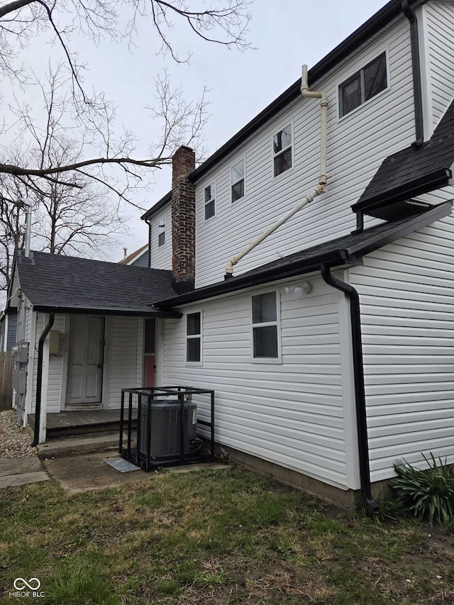 back of house featuring a chimney and central air condition unit