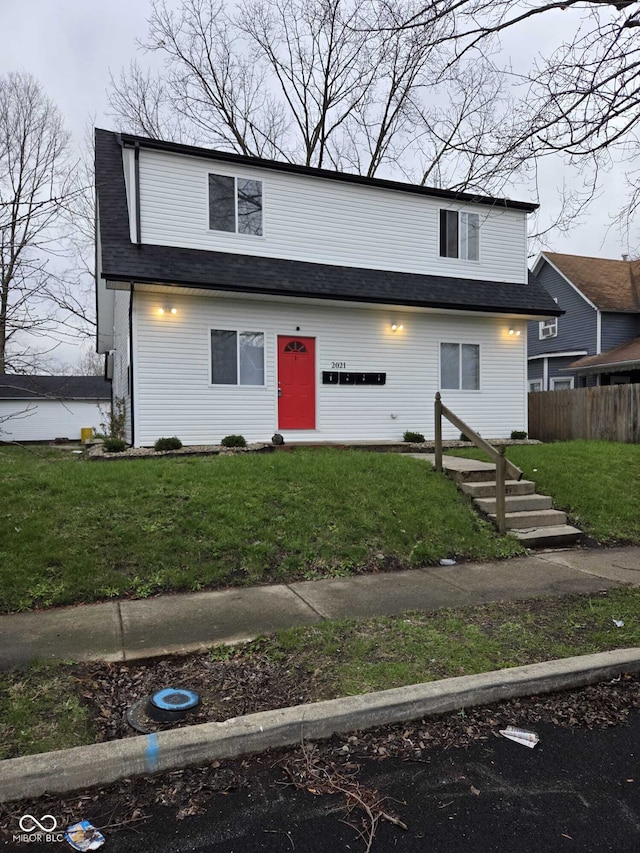 view of front facade featuring roof with shingles, a front yard, and fence