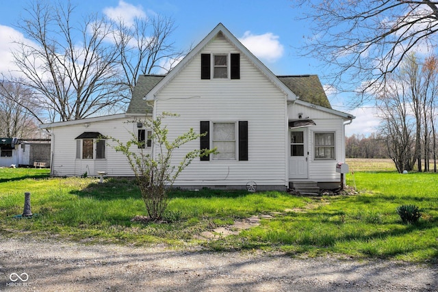 view of front of home with entry steps, a shingled roof, and a front yard