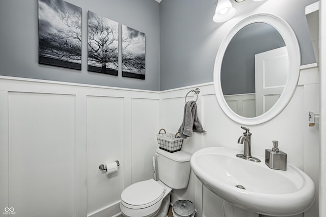 4644 Shelby Cir, Greenwood, IN 46143 - half bath featuring a sink, toilet, a decorative wall, and wainscoting