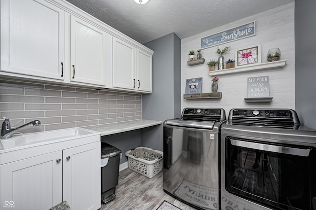 4644 Shelby Cir, Greenwood, IN 46143 - clothes washing area featuring a sink, light wood-type flooring, a textured ceiling, independent washer and dryer, and cabinet space