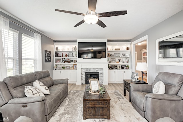 4644 Shelby Cir, Greenwood, IN 46143 - living area featuring a stone fireplace, light wood-type flooring, and a ceiling fan