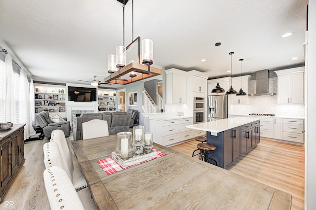 4644 Shelby Cir, Greenwood, IN 46143 - kitchen with wall chimney range hood, white cabinets, a ceiling fan, and appliances with stainless steel finishes