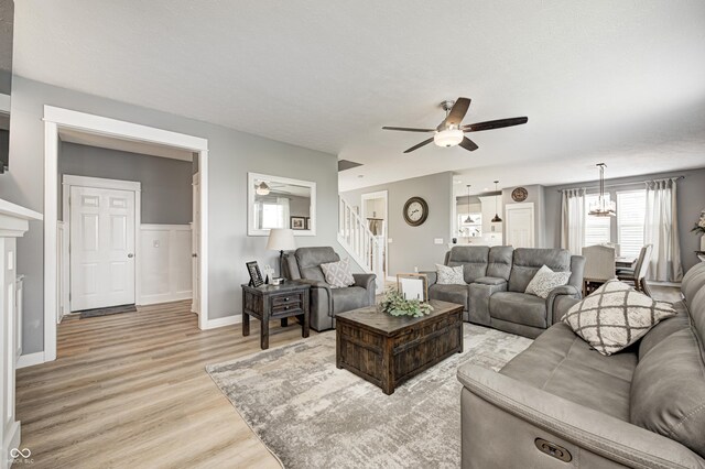 4644 Shelby Cir, Greenwood, IN 46143 - living room with baseboards, a fireplace, stairs, ceiling fan, and light wood finished floors