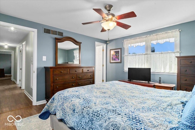 bedroom featuring visible vents, baseboards, a ceiling fan, and wood finished floors