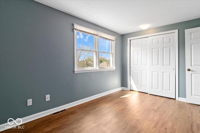 unfurnished bedroom with visible vents, baseboards, a closet, and wood finished floors