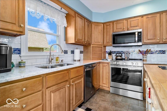 kitchen with a sink, decorative backsplash, light stone countertops, and stainless steel appliances