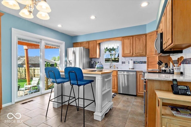 kitchen with an inviting chandelier, visible vents, appliances with stainless steel finishes, a breakfast bar area, and backsplash