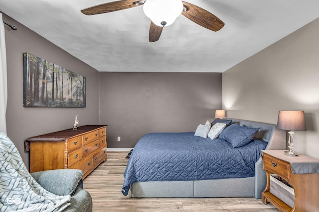 bedroom featuring light wood-style flooring, a ceiling fan, and baseboards