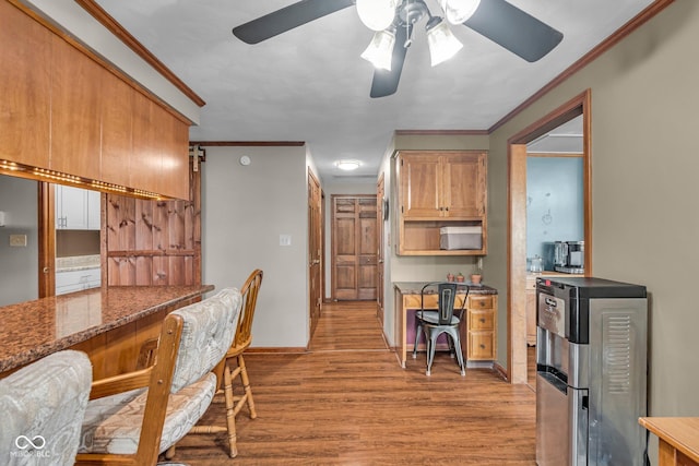 dining space featuring baseboards, light wood-type flooring, a ceiling fan, and ornamental molding