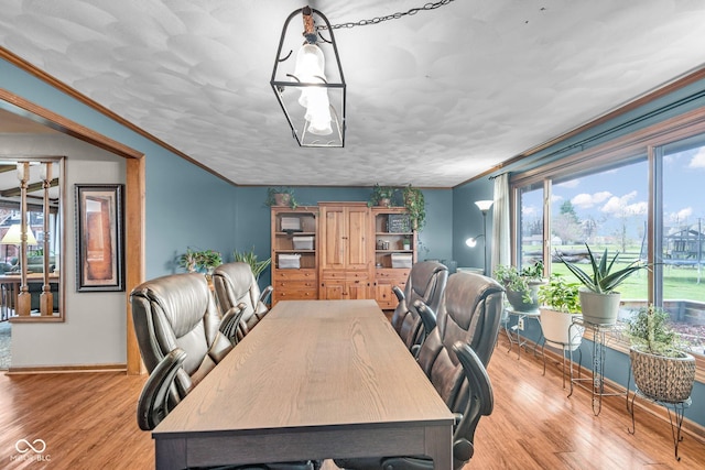 dining room with light wood-style floors, crown molding, and baseboards