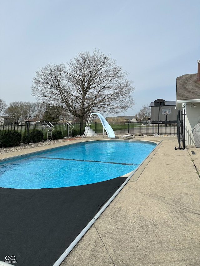 view of swimming pool featuring fence, a water slide, and a fenced in pool