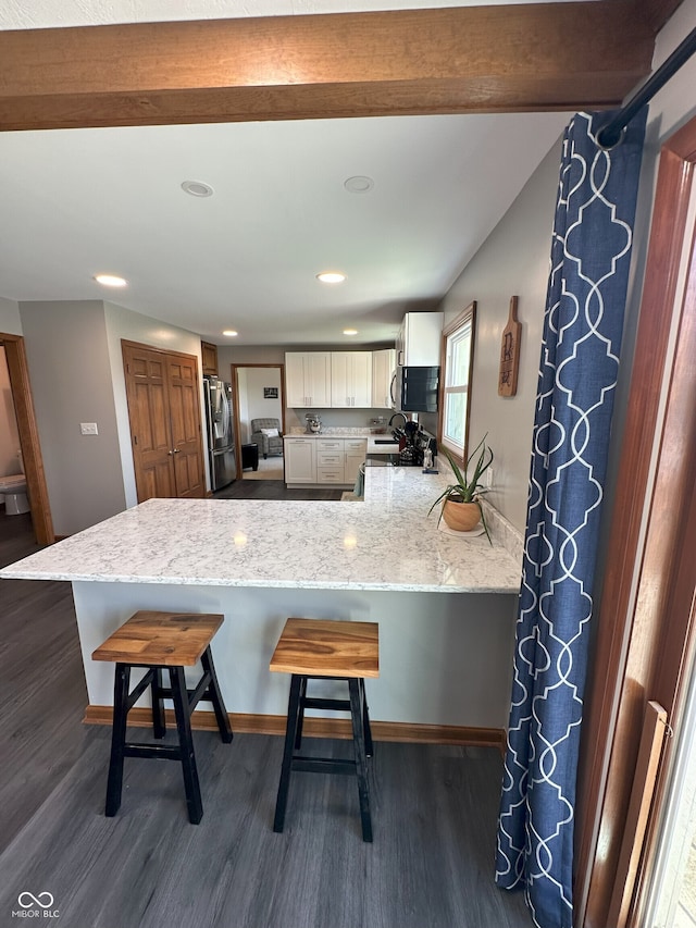 kitchen featuring dark wood-type flooring, a breakfast bar, a peninsula, and stainless steel appliances